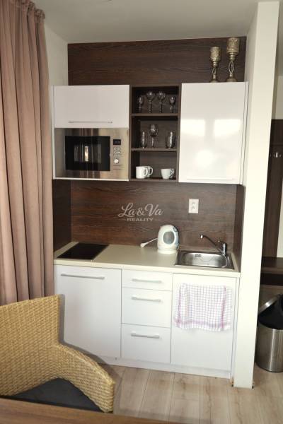 Na predaj veľký 49m2 apartmán Podhájská.  - Kompaktný kuchynský kút v 2-izbovom byte s bielymi skrinkami a spotrebičmi.