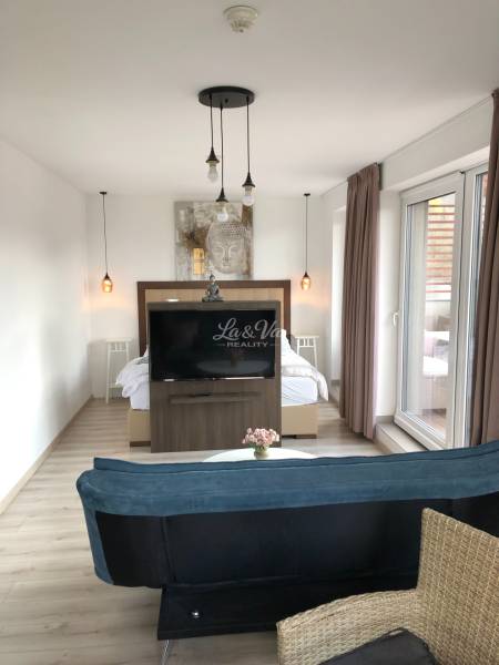 Na predaj štyri apartmány na jednom poschodí Podhájská - Obývacia izba v 2-izbovom byte s podlahou s dreveným dekorom a oddelenou spálňovou zónou.