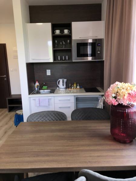 Na predaj štyri apartmány na jednom poschodí Podhájská - Kuchyňa v 2-izbovom byte s bielymi skrinkami a mikrovlnnou rúrou.