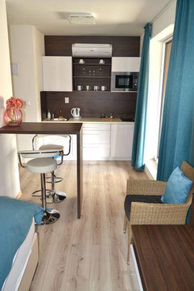 Na predaj štyri apartmány na jednom poschodí Podhájská - Kuchyňa v 2-izbovom byte s barovým pultom a podlahou s dreveným dekorom.