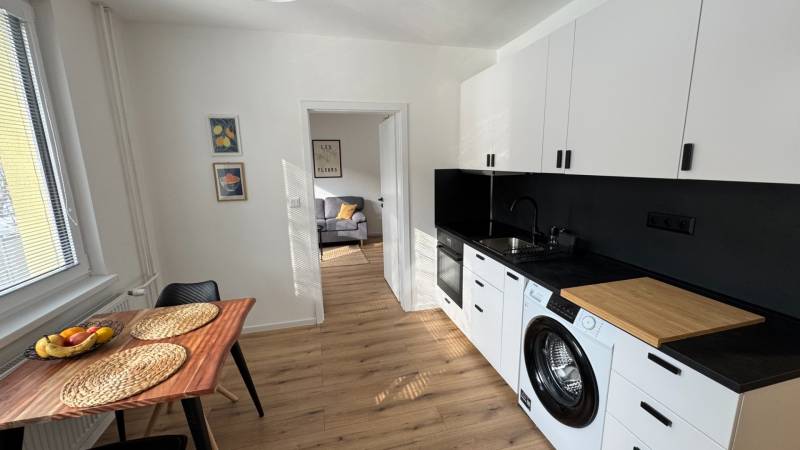 Exkluzívna ponuka moderného 1-izbového bytu s balkónom v meste Vráble - Kuchyňa v 1-izbovom byte s vybavením a podlahou s dreveným dekorom.