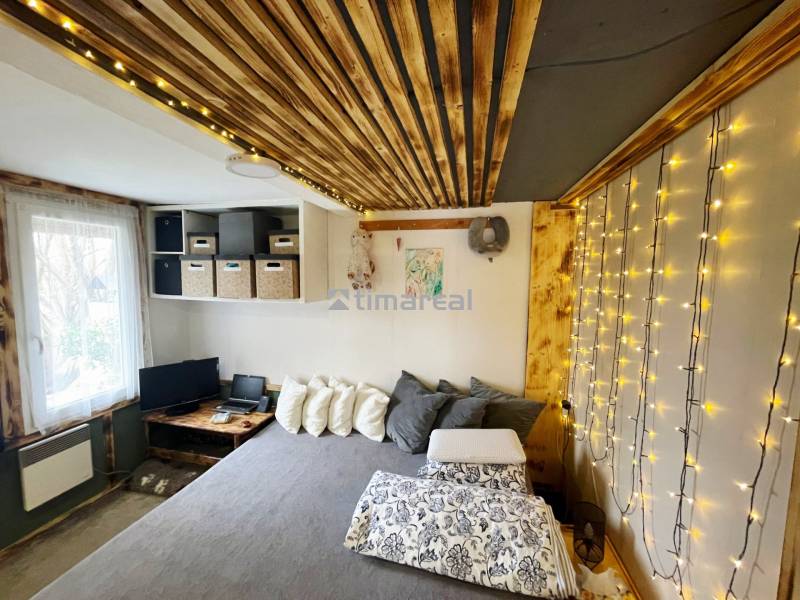 Bývanie v prírode, na dosah mesta, murov. chatka s celoročným využitím - Interiér rodinného domu so svetelnými reťazami, podlahou s dreveným dekorom a pohodlnou posteľou.