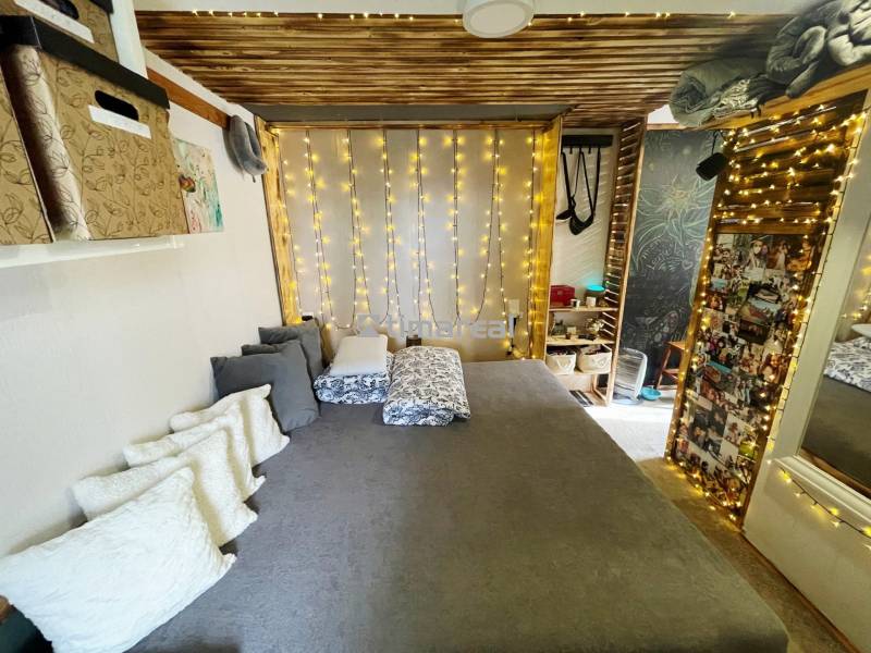 Bývanie v prírode, na dosah mesta, murov. chatka s celoročným využitím - Interiér rodinného domu s posteľou, vankúšmi a svetelnou dekoráciou.