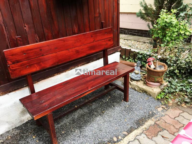 Bývanie v prírode, na dosah mesta, murov. chatka s celoročným využitím - Drevená lavička s rastlinou a ozdobnou dekoráciou pri rodinnom dome v Bohdanovciach nad Trnavou.