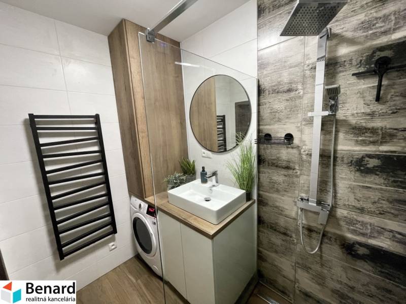 KOŠICE-2 IZBOVÝ BYT,NOVOSTAVBA,KOMPLET ZARIADENÝ,VL.PARK. MIESTO - Kúpeľňa v 2-izbovom byte s umývadlom, sprchou a práčkou, podlaha s dreveným dekorom.