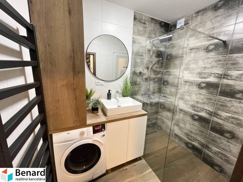 KOŠICE-2 IZBOVÝ BYT,NOVOSTAVBA,KOMPLET ZARIADENÝ,VL.PARK. MIESTO - Kúpeľňa so sprchovacím kútom, umývadlom, práčkou a podlahou s dreveným dekorom v 2-izbovom byte.