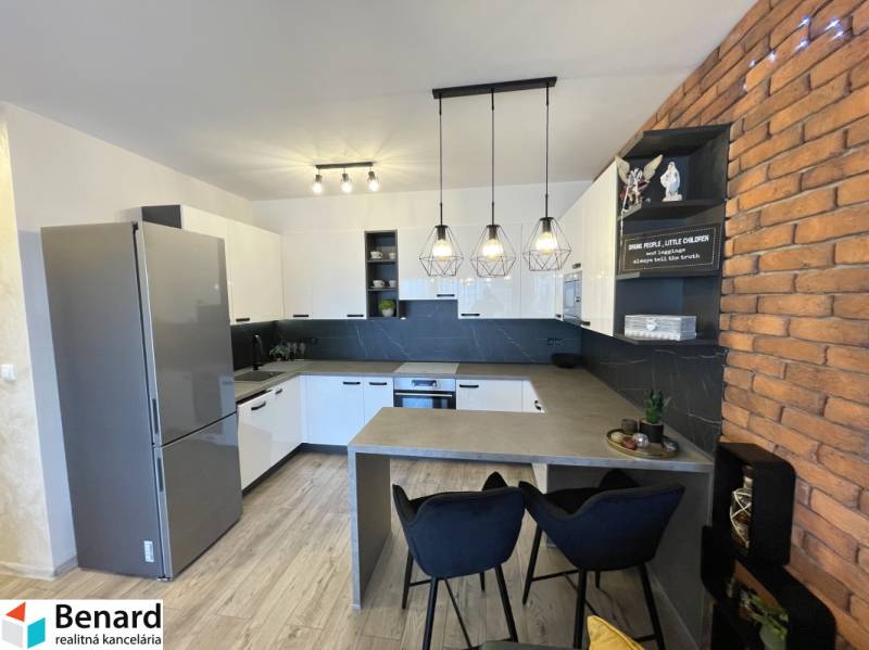 KOŠICE-2 IZBOVÝ BYT,NOVOSTAVBA,KOMPLET ZARIADENÝ,VL.PARK. MIESTO - Kuchyňa v 2-izbovom byte s podlahou s dreveným dekorom a tehlovým obkladom na stene.