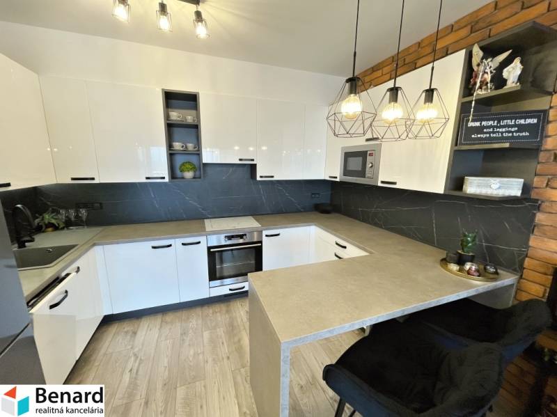 KOŠICE-2 IZBOVÝ BYT,NOVOSTAVBA,KOMPLET ZARIADENÝ,VL.PARK. MIESTO - Kuchyňa v 2-izbovom byte s bielymi skrinkami a podlahou s dreveným dekorom.