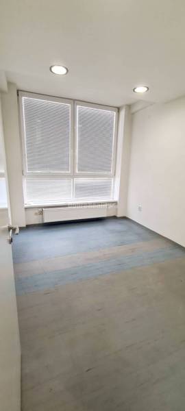 Dobré reality-na prenájom priestory 48,4 m2 a 30,90m2+ kúpelňa s wc, p - Miestnosť s veľkými oknami, podlahou s dreveným dekorom a radiátorom v Kancelárii.