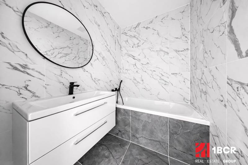 NOVÁ KOMPLET. REK., 3–IZB. BYT, PIVNICA, BALKÓN, DUKELSKÁ, BERNOLÁKOVO - Kúpeľňa s mramorovým obkladom, oválnym zrkadlom a moderným umývadlom v 3-izbovom byte.