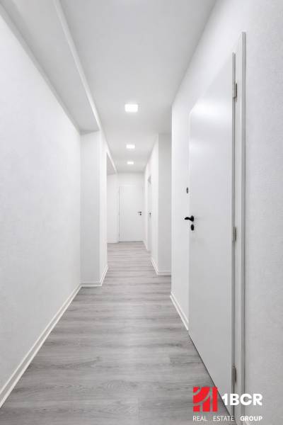 NOVÁ KOMPLET. REK., 3–IZB. BYT, PIVNICA, BALKÓN, DUKELSKÁ, BERNOLÁKOVO - Chodba s bielymi stenami a podlahou s dreveným dekorom v 3-izbovom byte.