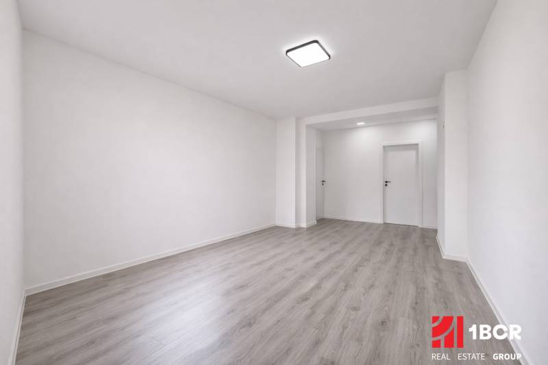 NOVÁ KOMPLET. REK., 3–IZB. BYT, PIVNICA, BALKÓN, DUKELSKÁ, BERNOLÁKOVO - Priestranná izba v 3-izbovom byte s podlahou s dreveným dekorom a bielymi stenami.