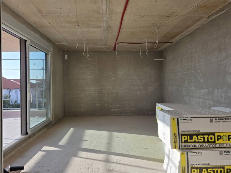 CHORVÁTSKO - Moderné apartmány 80 m od mora - SRIMA, VODICE - Prázdna miestnosť s betónovým stropom a veľkými oknami v 3-izbovom byte.