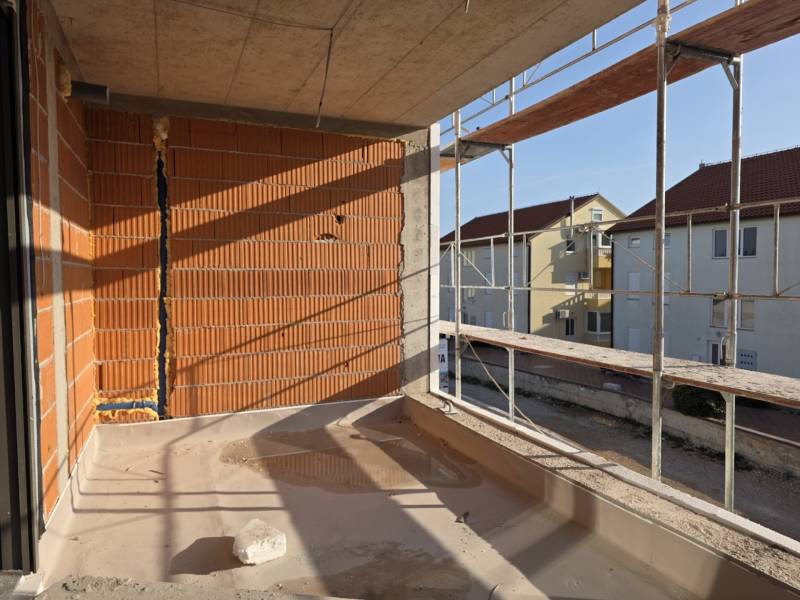 CHORVÁTSKO - Moderné apartmány 80 m od mora - SRIMA, VODICE - Stavebný proces na balkóne trojizbového bytu v meste Srima, lešenie a tehlové steny.
