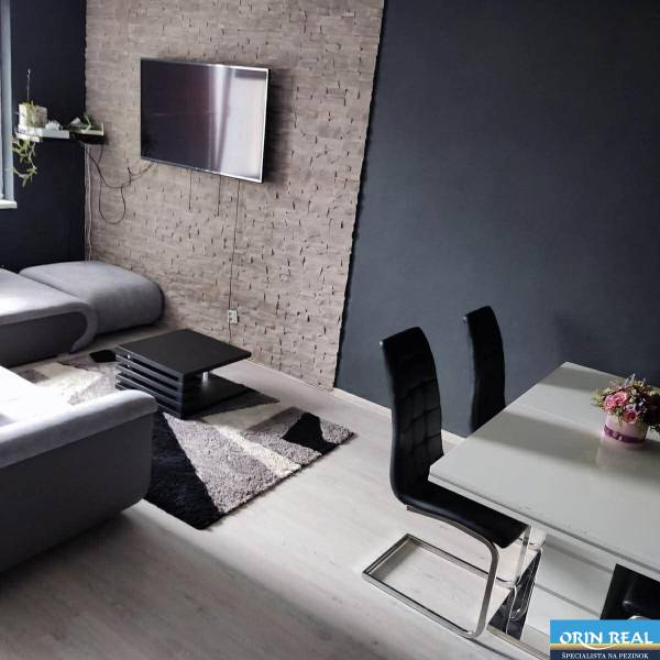 Na prenájom pekný 3izbový byt po rekonštrukcii 800,- Eur - Obývacia izba s televízorom, gaučom, čiernymi stoličkami a podlahou s dreveným dekorom.