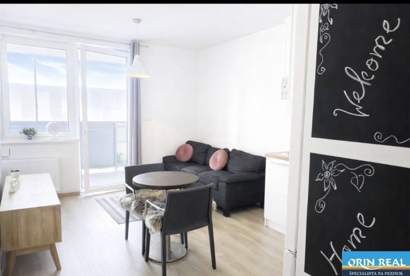 Na predaj 1,5 izbový apartmán v BA III Malokrasňanská 42,34m2 - Obývačka v 2-izbovom byte s podlahou s dreveným dekorom a balkónom.