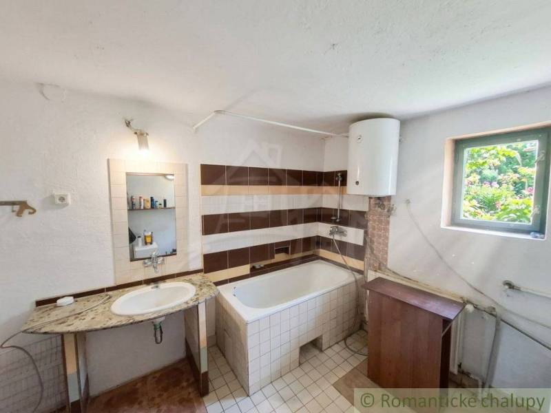 Vymeňte mestský hluk za ticho Bystričky: Domček s dušou a potenciálom - Kúpeľňa v rodinnom dome s umývadlom, vaňou a bojlerom.