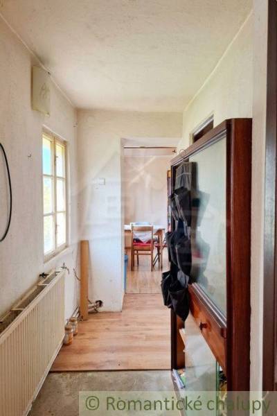 Vymeňte mestský hluk za ticho Bystričky: Domček s dušou a potenciálom - Interiér rodinného domu s úzkou chodbou a miestnosťou na konci.