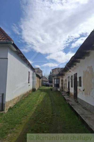 Vymeňte mestský hluk za ticho Bystričky: Domček s dušou a potenciálom - Ozdín: Starší rodinný dom so záhradou a oblačným nebom.