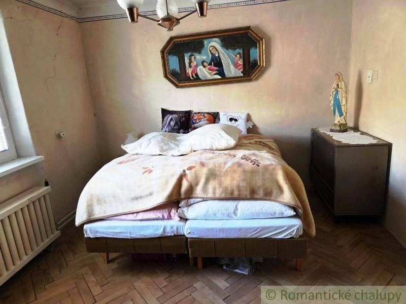Rodinný dom s 2 bytovými jednotkami, veľkým pozemkom a hospodárskym zá - Spálňa v rodinnom dome s posteľou a náboženskou dekoráciou na stene.