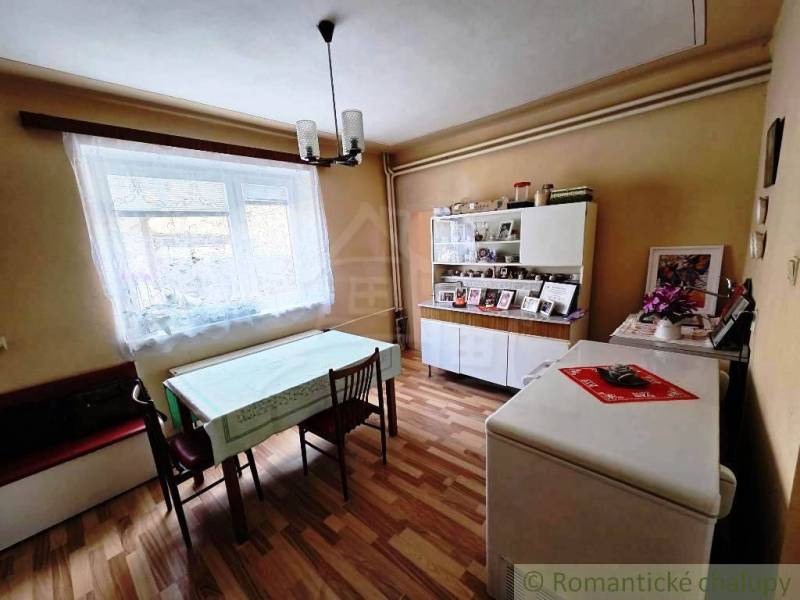 Rodinný dom s 2 bytovými jednotkami, veľkým pozemkom a hospodárskym zá - Jedáleň v rodinnom dome s podlahou s dreveným dekorom a jedálenským stolom.