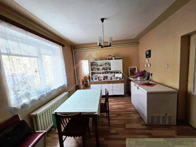 Rodinný dom s 2 bytovými jednotkami, veľkým pozemkom a hospodárskym zá - Jedáleň v rodinnom dome s podlahou s dreveným dekorom a jedálenským stolom.