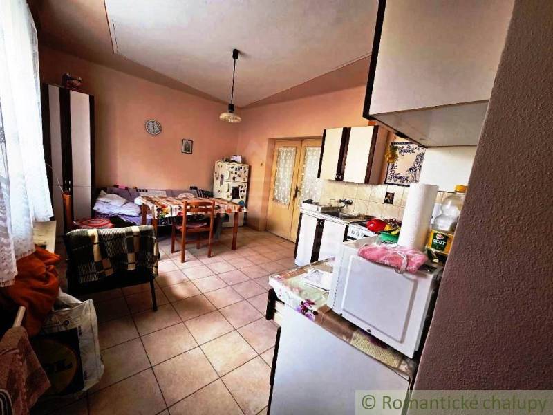 Rodinný dom s 2 bytovými jednotkami, veľkým pozemkom a hospodárskym zá - Kuchyňa v rodinnom dome s jedálenským stolom, kreslom a kuchynskými spotrebičmi.