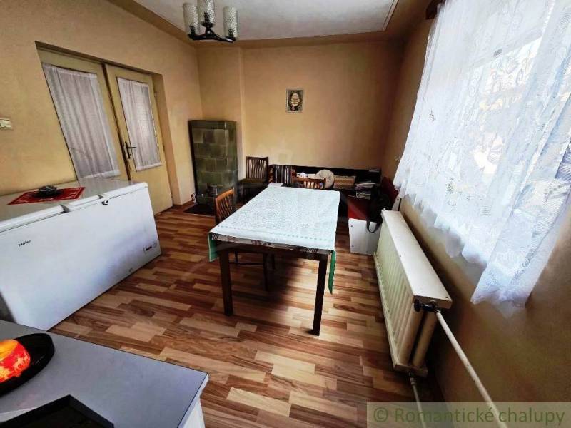 Rodinný dom s 2 bytovými jednotkami, veľkým pozemkom a hospodárskym zá - Jedáleň v rodinnom dome s podlahou s dreveným dekorom a kachľovou pecou.