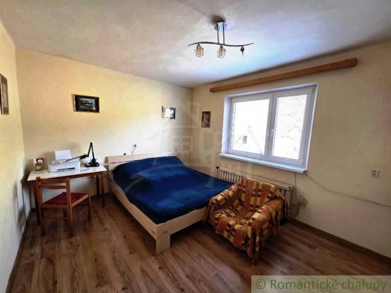 Rodinný dom s 2 bytovými jednotkami, veľkým pozemkom a hospodárskym zá - Spálňa s posteľou, stolom a stoličkou v rodinnom dome. Podlaha s dreveným dekorom.