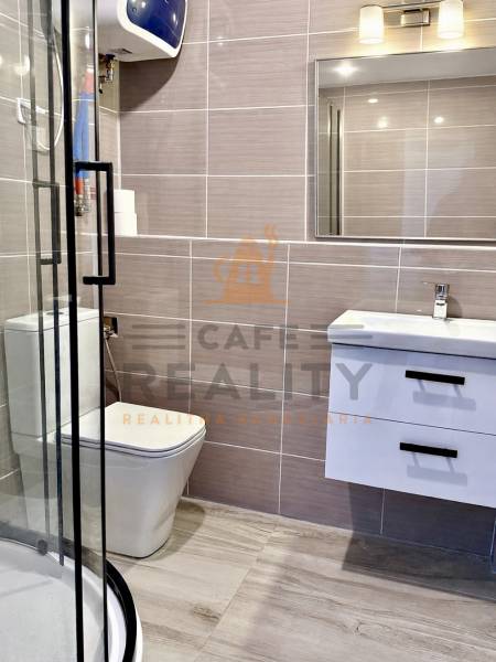 Na predaj 2 izbový murovaný domček, Bratislava, Záhorská Bystrica - Kúpeľňa v 2-izbovom byte, s sprchovým kútom, tmavými dlaždicami a podlahou s dreveným dekorom.