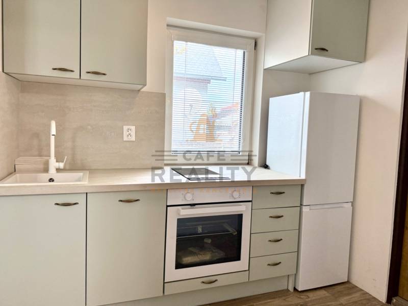 Na predaj 2 izbový murovaný domček, Bratislava, Záhorská Bystrica - Kuchyňa v 2-izbovom byte s umývadlom, rúrou a bielou chladničkou.