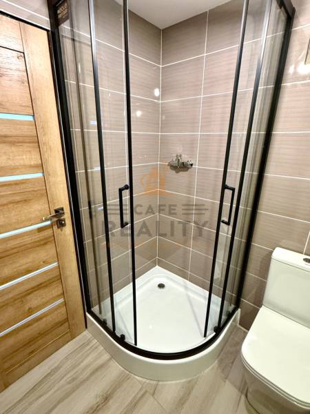 Na predaj 2 izbový murovaný domček, Bratislava, Záhorská Bystrica - Kúpeľňa v 2-izbovom byte s rohovým sprchovacím kútom a podlahou s dreveným dekorom.