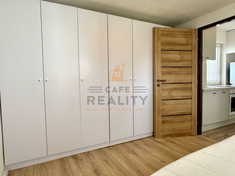 Na predaj 2 izbový murovaný domček, Bratislava, Záhorská Bystrica - Biela vstavaná skriňa, dvere s dreveným dekorom, pohľad do kuchyne v 2-izbovom byte.