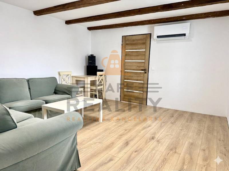 Na predaj 2 izbový murovaný domček, Bratislava, Záhorská Bystrica - Obývacia izba v rodinnom dome s drevenými trámami a podlahou s dreveným dekorom.