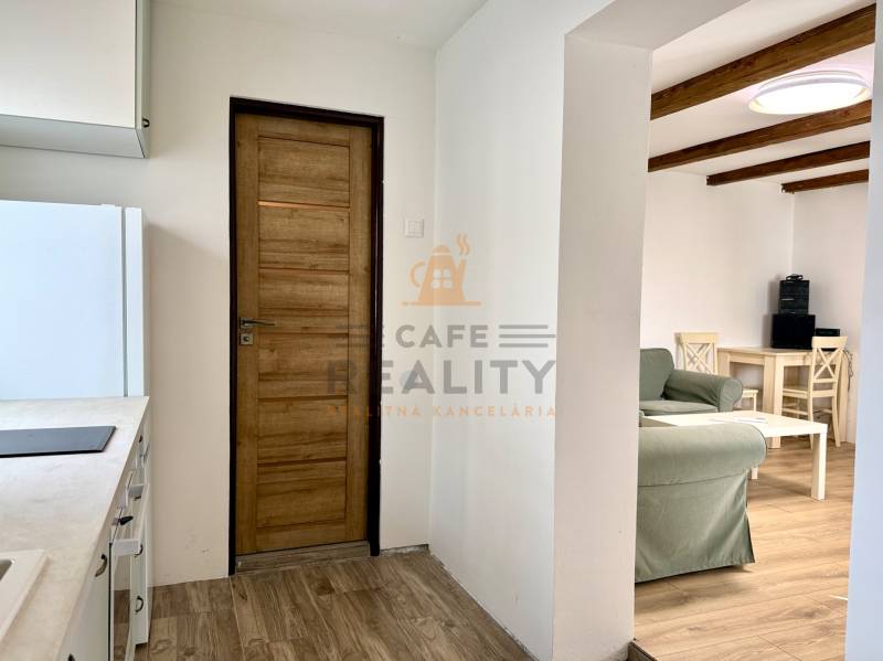 Na predaj 2 izbový murovaný domček, Bratislava, Záhorská Bystrica - Kuchyňa v 2-izbovom byte s podlahou s dreveným dekorom a drevenými trámami na strope.