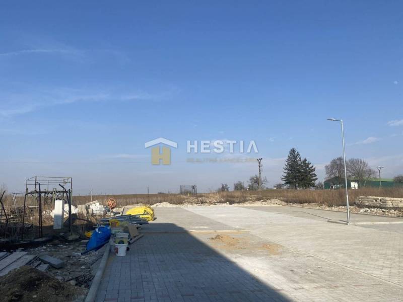 Posledný byt!! NA PREDAJ novostavba, 3-izb.byt, Petrova Ves - Stavba a exteriér s prázdnym pozemkom, modrá obloha, v pozadí stromy.