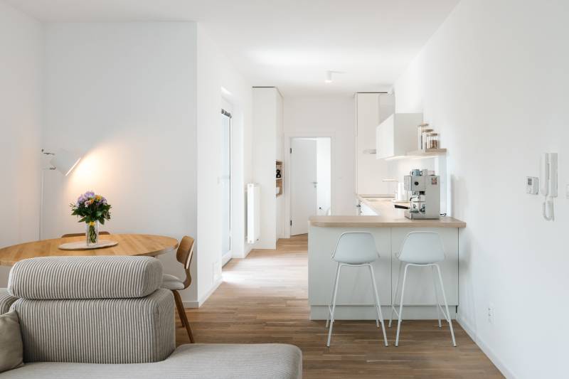 NUERA | PREDAJ 4i byt s predzáhradkou pri lese + 2x parking , BAIV - Kuchyňa so stolom, pohovkou a podlahou s dreveným dekorom v 4-izbovom byte.