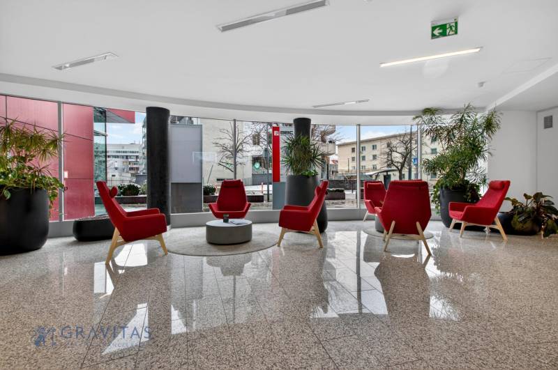 Kancelárie od 20m2 na PRENÁJOM | TOP biznis lokalita - Kancelárie s červenými kreslami, rastlinami a veľkými oknami s výhľadom na vonkajšie prostredie.