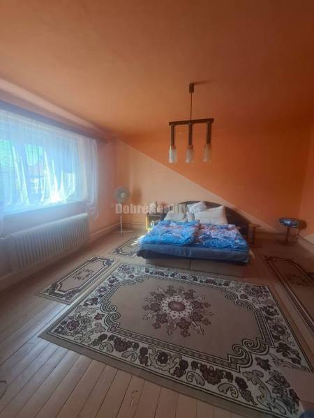 Na predaj rodinny dom v obci Iža. - Podkrovná spálňa v Rodinnom dome s farebnými stenami a dreveným dekorom podlahy.