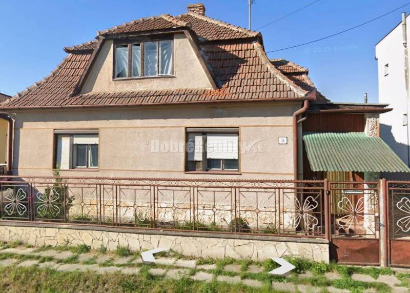 Na predaj rodinny dom v obci Iža. - Rodinný dom v Iži s tradičnou strechou a kvetinovým plotom.