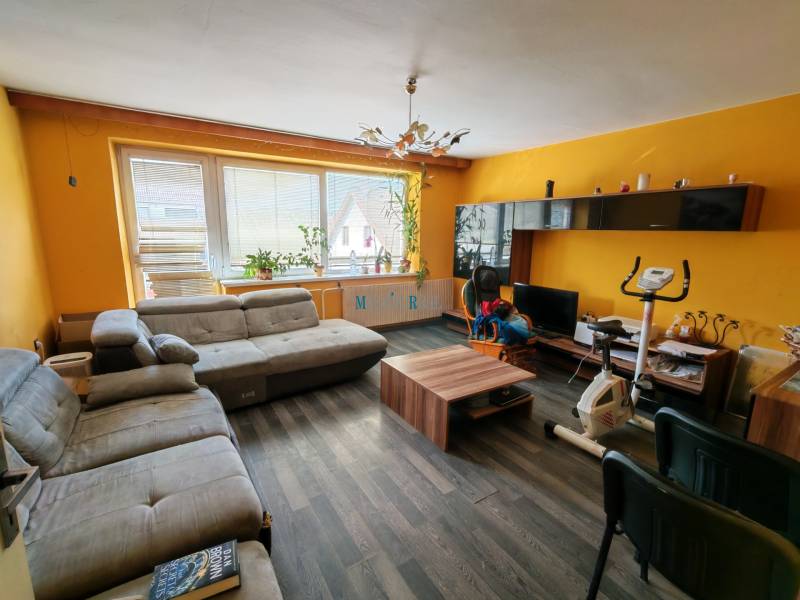 Na predaj 3-podlažný rodinný dom  v blízkosti centra Myjavy  - Obývacia izba rodinného domu s podlahou s dreveným dekorom a žltými stenami.