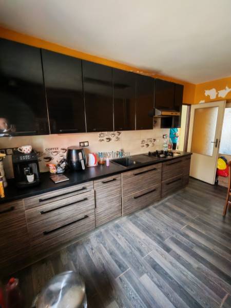 Na predaj 3-podlažný rodinný dom  v blízkosti centra Myjavy  - Kuchyňa s čiernymi skrinkami a podlahou s dreveným dekorom v rodinnom dome.