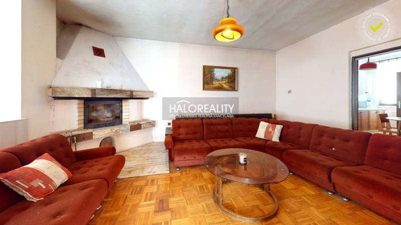 Predaj, rodinný dom Poltár - EXKLUZÍVNE HALO REALITY - Obývacia izba s krbom a pohovkou v rodinnom dome, s podlahou s dreveným dekorom.