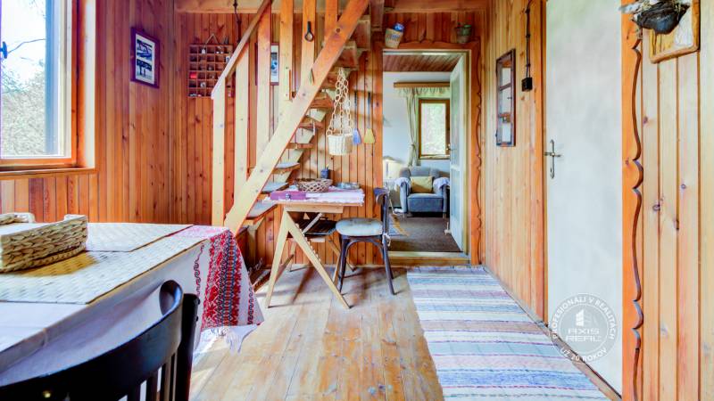 Dvojpodlažná chata v krásnom prostredí Buková, okr. Trnava - Drevená chata s drevenými stenami, schodiskom a stolom, útulné sedenie.