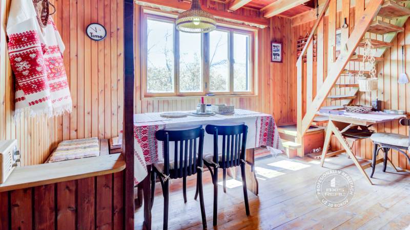 Dvojpodlažná chata v krásnom prostredí Buková, okr. Trnava - Drevený interiér chaty s jedálenským stolom, stoličkami a dekoratívnymi prvkami v tradičnom štýle.