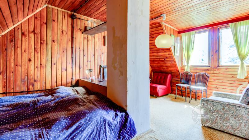 Dvojpodlažná chata v krásnom prostredí Buková, okr. Trnava - Izba v chate s drevenými stenami, červeným kreslom a zelenými závesmi.