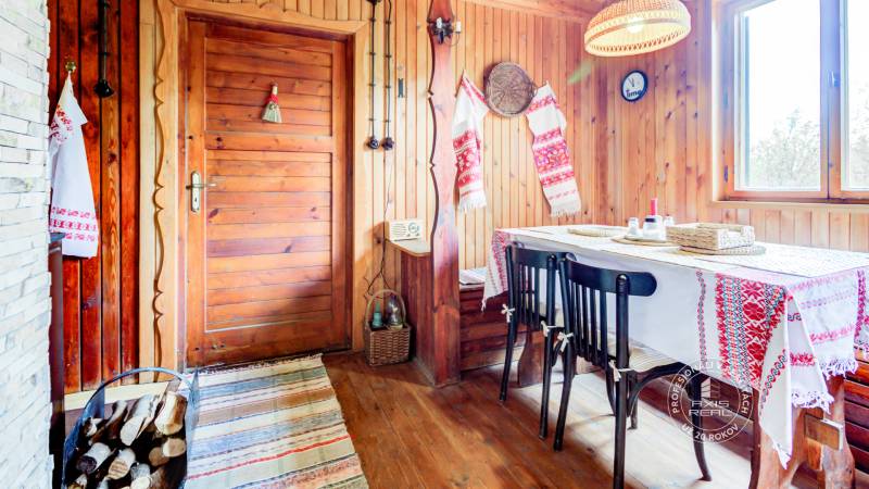 Dvojpodlažná chata v krásnom prostredí Buková, okr. Trnava - Rustikálny interiér chaty s drevenými stenami a tradičnými výšivkami na dečkách.