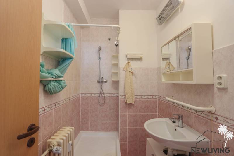 Na prenájom 2 izbový byt v Piešťanoch - Kúpeľňa v 2-izbovom byte s ružovými obkladmi, umývadlom a sprchovým kútom.