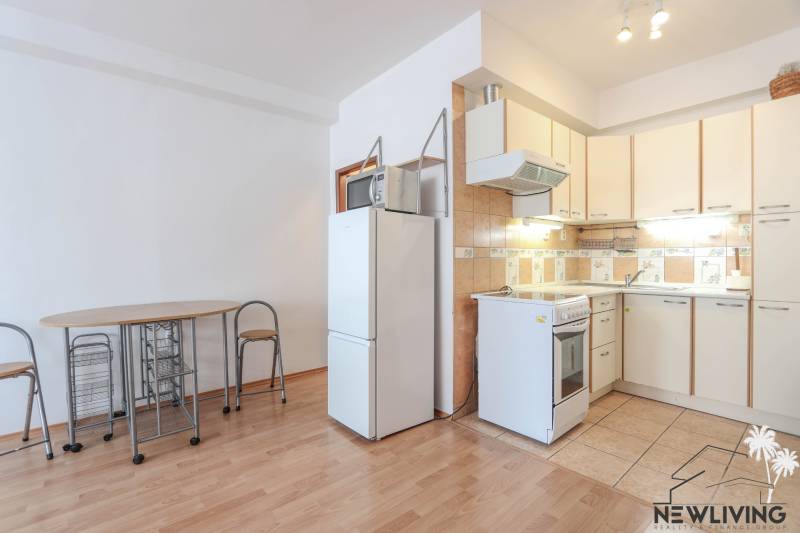 Na prenájom 2 izbový byt v Piešťanoch - Kuchyňa v 2-izbovom byte s podlahou s dreveným dekorom, jedálenským stolom a chladničkou.