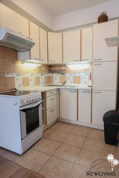 Na prenájom 2 izbový byt v Piešťanoch - Kuchyňa v 2-izbovom byte s bielymi skrinkami a sporákom, podlaha s dreveným dekorom.